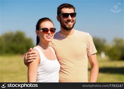 people and relationships concept - happy couple in sunglasses outdoors in summer. happy couple in sunglasses outdoors in summer