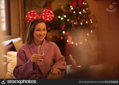 people, and relaxation concept beautiful young woman in bath robe drinking champagne at spa over holidays lights background