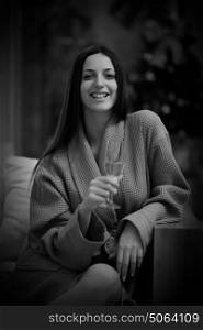 people, and relaxation concept beautiful young woman in bath robe drinking champagne at spa over holidays lights background
