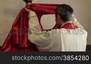 People and religion, hispanic catholic priest dressing in church before serving mass with cross in background. With model release