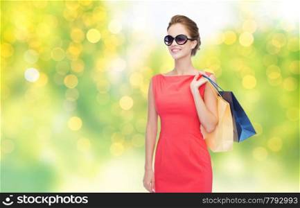 people and sale concept - beautiful smiling woman with shopping bags over green background and lights. beautiful woman with shopping bags over lights