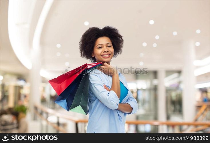 people and sale concept - smiling afro american woman with shopping bags over mall background. smiling afro american woman with shopping bags