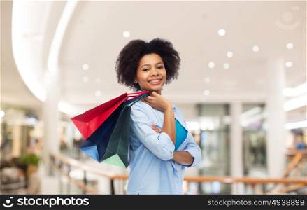 people and sale concept - smiling afro american woman with shopping bags over mall background. smiling afro american woman with shopping bags