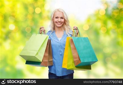 people and sale concept - young smiling woman with shopping bags over green background and lights. young woman with shopping bags over lights