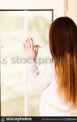 People and solitude concept. alone woman long hair looking dreaming through window back view indoor