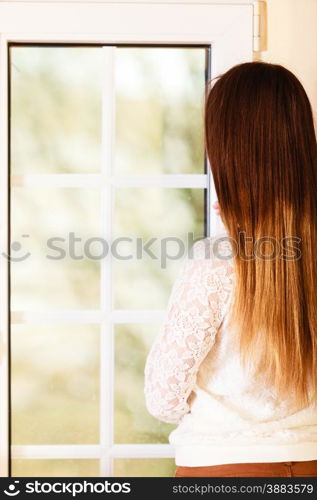 People and solitude concept. alone woman long hair looking dreaming through window back view indoor