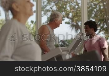 People and sports, young man at work as personal trainer and helping elderly couple working out in fitness gym