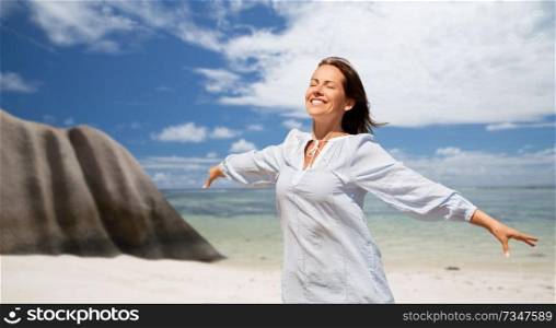 people and summer concept - happy smiling woman enjoying sun over seychelles island tropical beach background. happy woman over seychelles island tropical beach