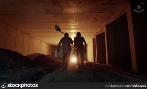 People and teamwork, team of two men at work in new site, construction workers walking together in underground tunnel. Part 10 of 11