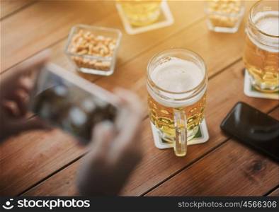 people and technology concept - close up of hands with smartphone picturing beer at bar. close up of hands with smartphone picturing beer