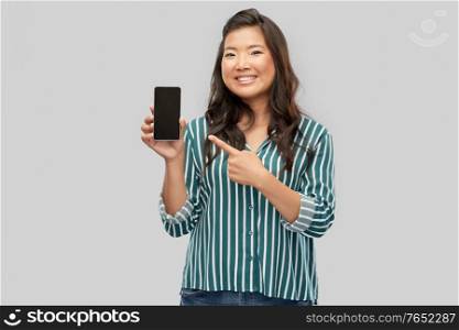 people and technology concept - happy asian young woman with smartphone over grey background. happy asian woman over grey background