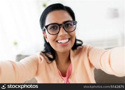 people and technology concept - happy smiling indian woman taking selfie at home. happy smiling woman taking selfie at home