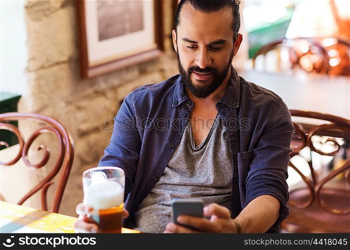 people and technology concept - man with smartphone drinking beer and reading message at bar or pub. man with smartphone drinking beer at bar or pub