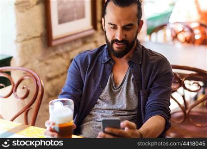 people and technology concept - man with smartphone drinking beer and reading message at bar or pub. man with smartphone drinking beer at bar or pub