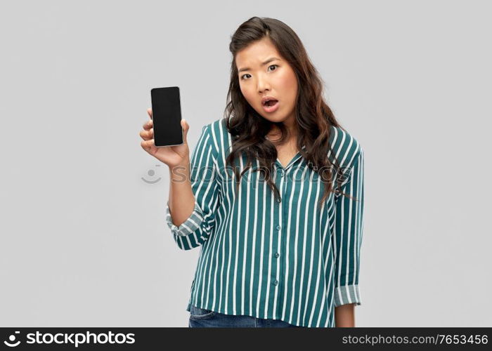 people and technology concept - shocked asian young woman with smartphone over grey background. shocked asian woman over grey background