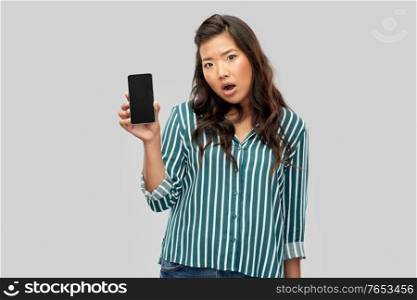 people and technology concept - shocked asian young woman with smartphone over grey background. shocked asian woman over grey background