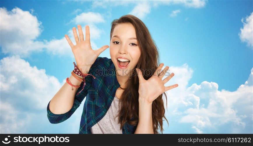 people and teens concept - happy laughing pretty teenage girl showing hands over blue sky and clouds background. happy laughing pretty teenage girl showing hands