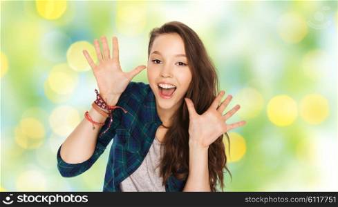 people and teens concept - happy laughing pretty teenage girl showing hands over green summer holidays lights background. happy laughing pretty teenage girl showing hands