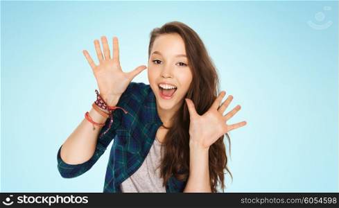 people and teens concept - happy laughing pretty teenage girl showing hands over blue background. happy laughing pretty teenage girl showing hands