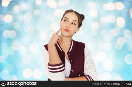 people and teens concept - happy pretty teenage girl thinking over blue holidays lights background. happy pretty teenage girl thinking
