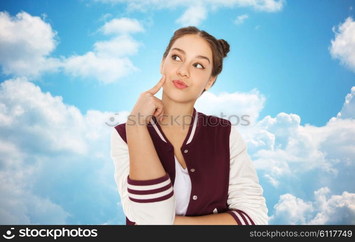 people and teens concept - happy pretty teenage girl thinking over blue sky and clouds background. happy pretty teenage girl thinking