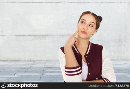 people and teens concept - happy pretty teenage girl thinking over gray urban street background. happy pretty teenage girl thinking