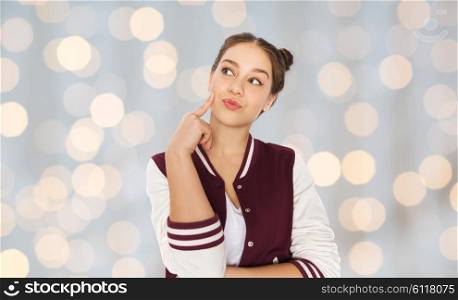 people and teens concept - happy pretty teenage girl thinking over holidays lights background. happy pretty teenage girl thinking