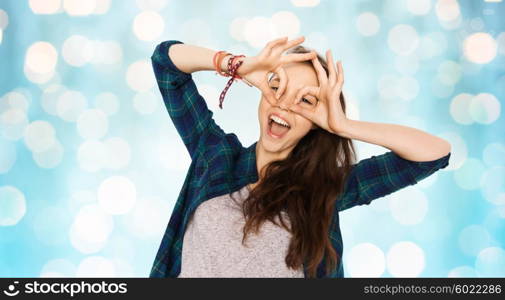 people and teens concept - happy smiling pretty teenage girl making face and having fun over blue holidays lights background. happy teenage girl making face and having fun