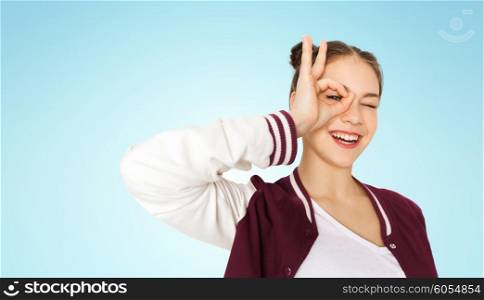 people and teens concept - happy smiling pretty teenage girl making face and having fun over blue background. happy teenage girl making face and having fun