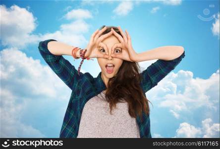 people and teens concept - happy smiling pretty teenage girl making face and having fun over blue sky and clouds background. happy teenage girl making face and having fun