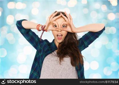 people and teens concept - happy smiling pretty teenage girl making face and having fun over blue holidays lights background. happy teenage girl making face and having fun