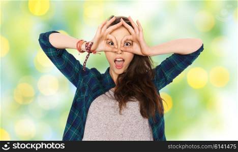 people and teens concept - happy smiling pretty teenage girl making face and having fun over green summer holidays lights background. happy teenage girl making face and having fun