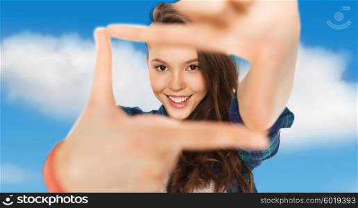 people and teens concept - happy smiling pretty teenage girl making frame of fingers over blue sky and clouds background. happy teenage girl making frame of fingers