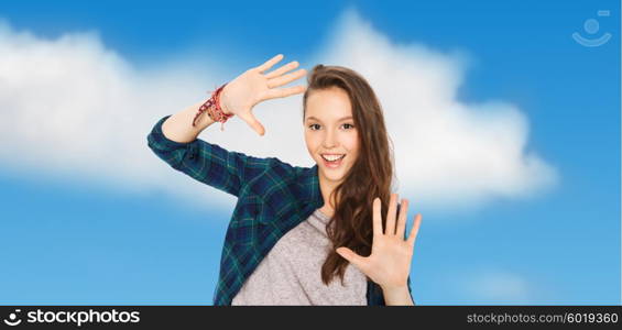 people and teens concept - happy smiling pretty teenage girl showing hands over blue sky and clouds background. happy smiling pretty teenage girl showing hands