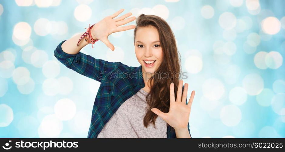 people and teens concept - happy smiling pretty teenage girl showing hands over blue holidays lights background. happy smiling pretty teenage girl showing hands