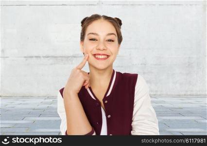 people and teens concept - happy smiling pretty teenage girl with eye makeup over gray urban street background. happy smiling pretty teenage girl