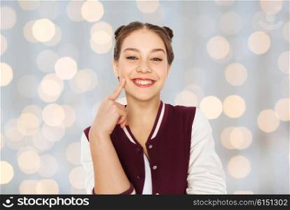 people and teens concept - happy smiling pretty teenage girl with eye makeup over holidays lights background. happy smiling pretty teenage girl