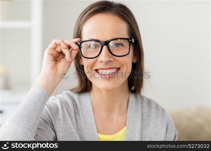 people and vision concept - happy smiling middle aged woman in glasses at home. happy smiling middle aged woman in glasses at home