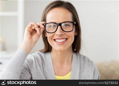 people and vision concept - happy smiling middle aged woman in glasses at home. happy smiling middle aged woman in glasses at home