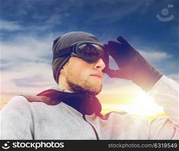 people and winter sport concept - young man in ski goggles outdoors. sports man with ski goggles in winter outdoors