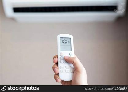 People are holding a remote control of air conditioners, 25 degrees Celsius to save electricity in the house.