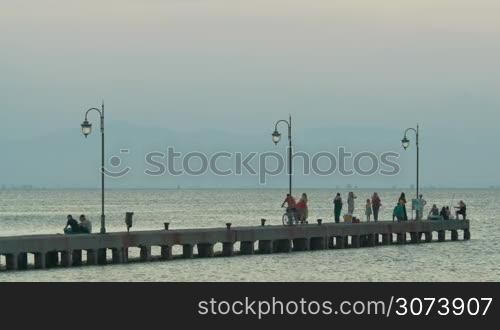 People are walking along the pier at dawn, shot of daily life.