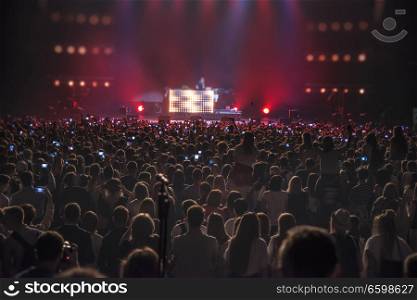 people at the concert with the phones shoot the show