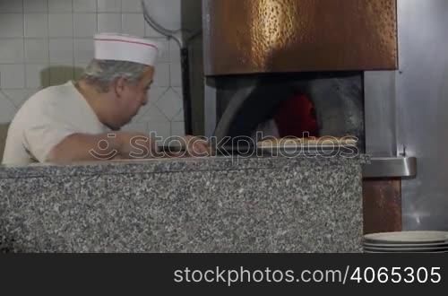 People at work, man working, food preparation, job, profession. Portrait of happy professional cook smiling, skilled chef cooking pizza in wood oven in Italian restaurant kitchen. 10 of 14