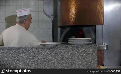 People at work, man working, food preparation, jobs, professions. Portrait of happy professional cook smiling, baker, caucasian chef cooking pizza in wood oven in restaurant kitchen in Italy. 14 of 14