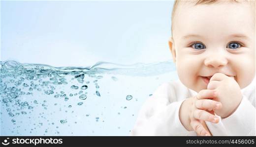 people, babyhood, child care and advertisement concept - close up of happy baby boy over blue background with water splash