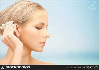 people, beauty and beach concept - beautiful woman with seashell over blue background
