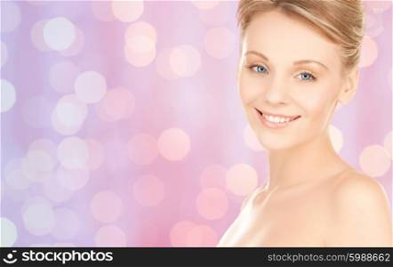 people, beauty and body care concept - lovely woman face over pink lights background