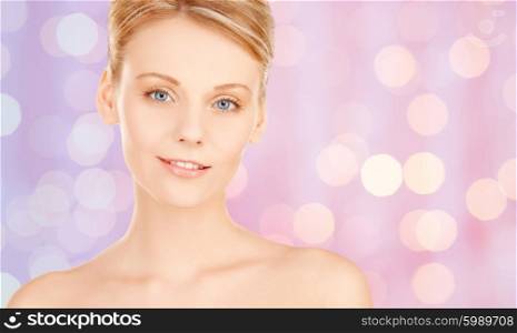 people, beauty and body care concept - lovely woman face over pink lights background
