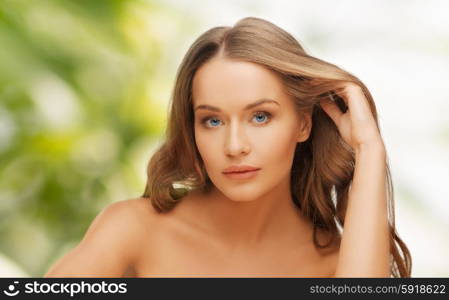 people, beauty and hair care concept - beautiful woman face with long blond hair over green natural background